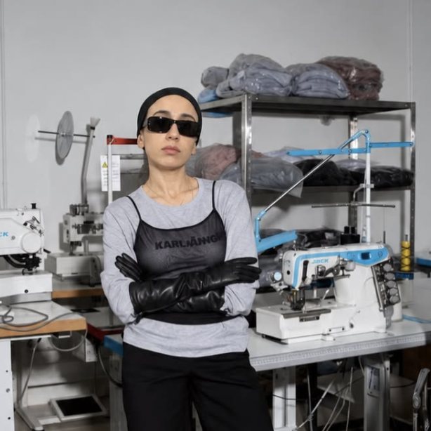 Ani Chopurian in sunglasses, leather gloves and boots in a sewing workshop