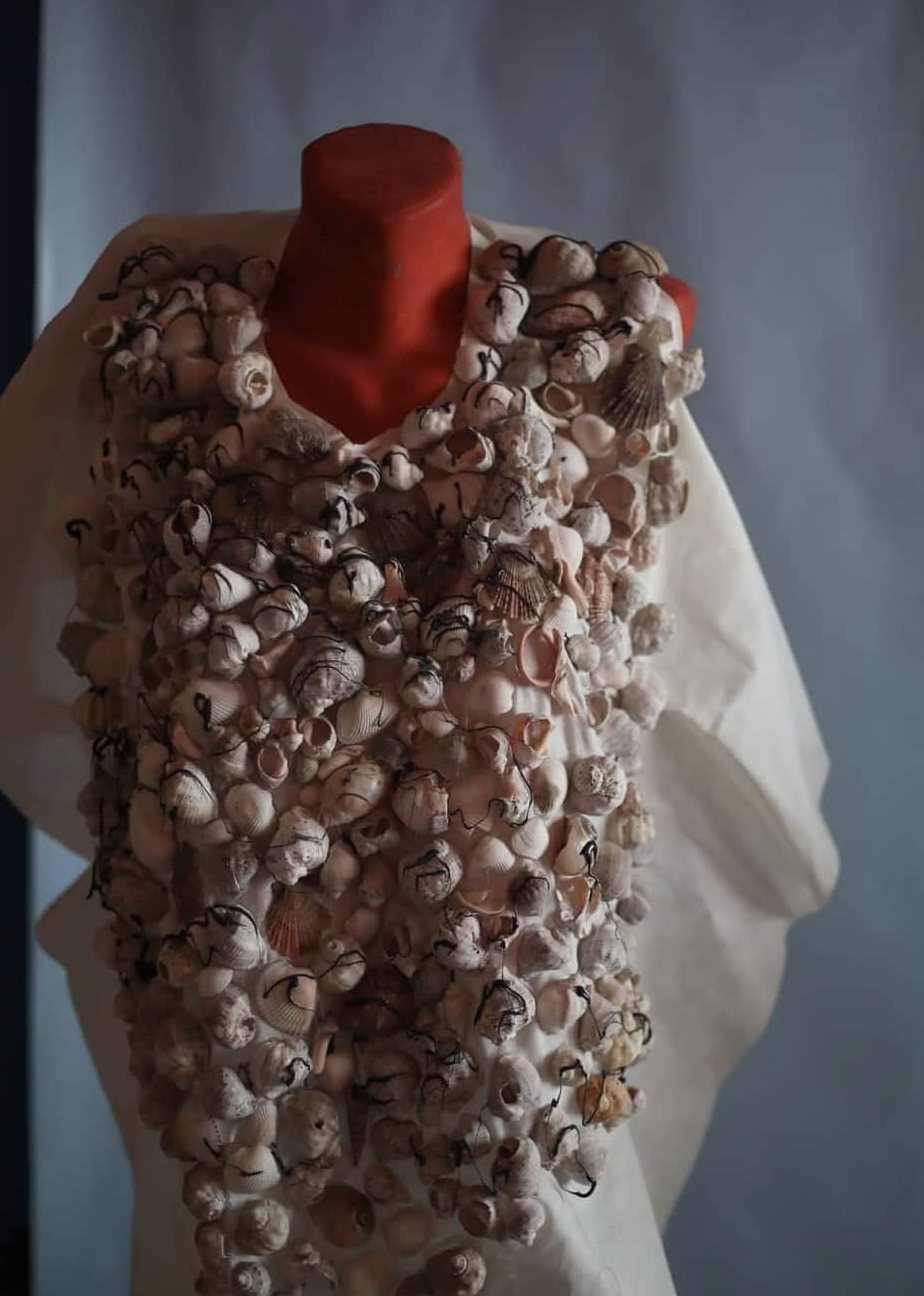 Hand-made bodice covered in hundreds of seashells stitched with black thread, on a mannequin